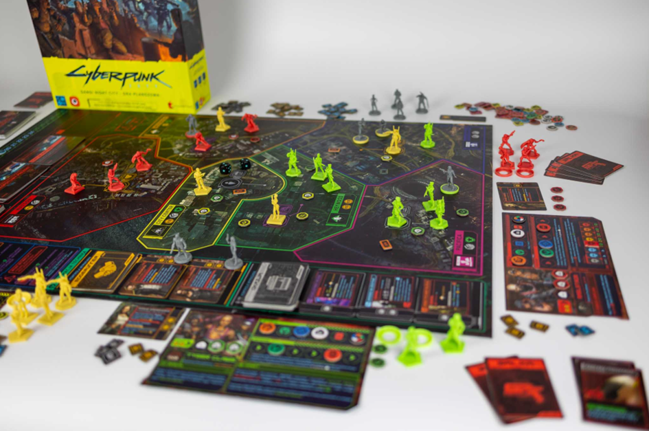 Gra planszowa Cyberpunk 2077 – plansza z figurkami, kartami i akcesoriami na stole.